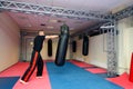 Young kickboxer kicking and punching punching bag in sport gym