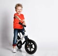 Young kid boy in orange t-shirt and blue jeans biker happy to ride new cool bicycle