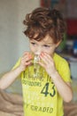 Young kid, boy starts his morning with a glass of fresh water. Curly little boy drinks water. Water concept