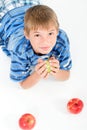 Young kid laying on the floor holding an apple.