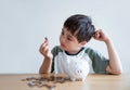 Young kid looking at coin on his hands, Child boy putting coins into piggy bank, Child counting saving money, Children learning Royalty Free Stock Photo