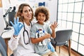 Young kid at pediatrician clinic holding teddy bear doing ok sign with fingers, smiling friendly gesturing excellent symbol Royalty Free Stock Photo