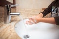 Young kid washing and rubbing his palm hands with soap before rinsing off during pandemia as learned in school and at home