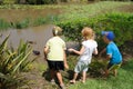 Young kids feeding ducks in pond
