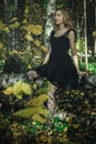 A young kind witch in a black dress with a black mask in a mystical forest in various poses. Art processing