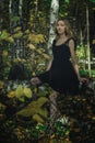 A young kind witch in a black dress with a black mask in a mystical forest in various poses. Art processing