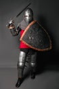 A young knight in medieval armor with a weapon in his hands kneeled Royalty Free Stock Photo