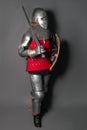 A young knight in medieval armor with a weapon in his hands kneeled Royalty Free Stock Photo