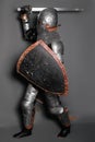 A young knight in medieval armor with a weapon in his hands kneeled Royalty Free Stock Photo