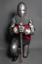 A young knight in medieval armor with a weapon in his hands kneeled Royalty Free Stock Photo