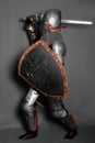 A young knight in medieval armor with a weapon in his hands kneeled Royalty Free Stock Photo
