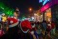 Young ladies with red santa claus hats enjoying themselves at illuminated and decorated park street with lights with year end Royalty Free Stock Photo