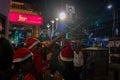 Young ladies with red santa claus hats enjoying themselves at illuminated and decorated park street with lights with year end Royalty Free Stock Photo