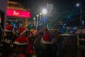 Young ladies with red santa claus hats enjoying themselves at illuminated and decorated park street with lights with year end Royalty Free Stock Photo