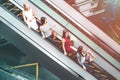 Young ladies are riding on escalator. They are standing one after another. Each of them has shopping bags. They are Royalty Free Stock Photo