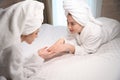 Young ladies talking about nails while lying On bed together Royalty Free Stock Photo