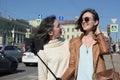 Young ladies tourists make selfies at a bridge in Saint Petersburg, Russia, and have fun in front of camera