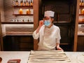 14-11-2020: young lady baker explains to customers how to make Italian grissini bread sticks, a long thin crisp bread baked from