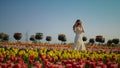 Young lady with camera making photo of beautiful tulips. Girl walking in park. Royalty Free Stock Photo