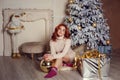 young lady with curlu hair gifts by the fireplace near the Christmas tree. New year concept Royalty Free Stock Photo