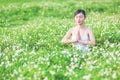 Young lady doing yoga exercise in green field with small white flowers outdoor area showing calm peaceful in meditation mind