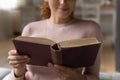 Young lady engaged in reading old book in shabby cover