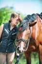 Young lady equestrian standing close to her lovely chestnut horse