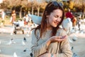 Young lady feeds pigeons on the square of the city