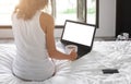 Young lady freelancer sitting on the bed in hotel room Royalty Free Stock Photo