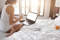 Young lady freelancer sitting on the bed in hotel room Royalty Free Stock Photo