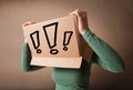 Young lady gesturing with a cardboard box on her head with exclamation point