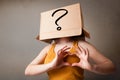 Young lady gesturing with a cardboard box on her head with quest