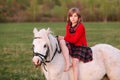 Young lady girl in red dress sitting on a white pony Royalty Free Stock Photo