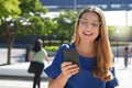 Young lady with glasses checking her mobile phone outdoors