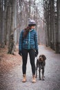 Young lady with her dog in beautiful forest on a morning walk. Connection between a dog and woman. Relationship of mutual trust.