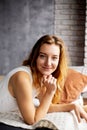 A young lady, her long hair cascading, lounges on a pillow in a white shirt, embodying tranquility and serenity Royalty Free Stock Photo