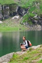 Young lady hiker with backpack sitting on mountain Royalty Free Stock Photo