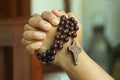 Young junior woman holding rosary in hand. Clasped hands praying holding a rosary with Jesus Christ Cross or Crucifix. Royalty Free Stock Photo