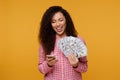 Young lady isolated over blue background. Looking camera showing display of mobile phone holding money Royalty Free Stock Photo