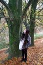 Young lady with long brunette hair looking up at autumn tree Royalty Free Stock Photo