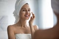 Young lady look in mirror use facial lotion in morning Royalty Free Stock Photo