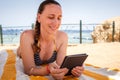 Young lady lounging and reading book in the shadow at the beach Royalty Free Stock Photo