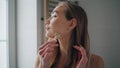 Young lady massaging face in bath room portrait. Fresh girl using jade roller