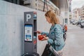 young lady paying for her parking ticket using credit card at pay station terminal on city street outdoors Royalty Free Stock Photo