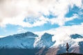 A young lady photographer with a stunning scenery of rocky mountain covered with snow after the raining day. Cloudy and foggy. Royalty Free Stock Photo