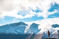 A young lady photographer with a stunning scenery of rocky mountain covered with snow after the raining day. Cloudy and foggy. Royalty Free Stock Photo