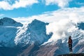 A young lady photographer with a stunning scenery of rocky mountain covered with snow after the raining day. Cloudy and foggy. Royalty Free Stock Photo