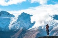 A young lady photographer with a stunning scenery of rocky mountain covered with snow after the raining day. Cloudy and foggy. Royalty Free Stock Photo