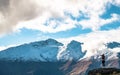 A young lady photographer with a stunning scenery of rocky mountain covered with snow after the raining day. Cloudy and foggy. Royalty Free Stock Photo