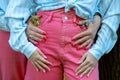 Young lady in pink skinny jeans and blue shirt. Blue fowers in pants pocket. Hands lie beautifully on stylish jeans. Royalty Free Stock Photo